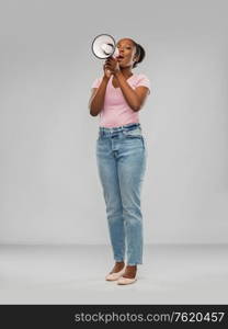 communication, feminism and human rights concept - african american young woman speaking to megaphone over grey background. african american woman over grey background