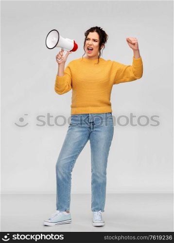 communication, feminism and people concept - angry young woman with pierced nose speaking to megaphone over grey background. angry young woman speaking to megaphone