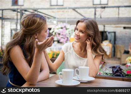 communication, friendship and people concept - happy young women drinking coffee at outdoor cafe. happy young women drinking coffee at outdoor cafe