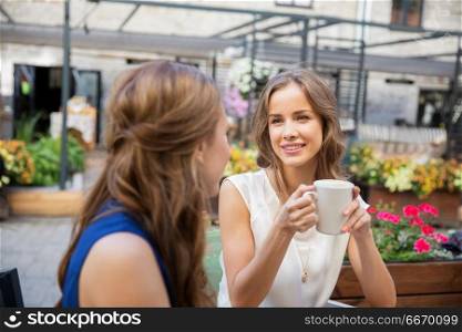 communication, friendship and people concept - happy young women drinking coffee at outdoor cafe. happy young women drinking coffee at outdoor cafe. happy young women drinking coffee at outdoor cafe