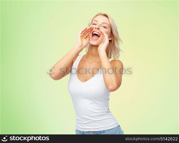 communication, information and people concept - happy beautiful young woman in white top and jeans with blonde hair shouting or calling someone over green background. happy young woman shouting or calling someone