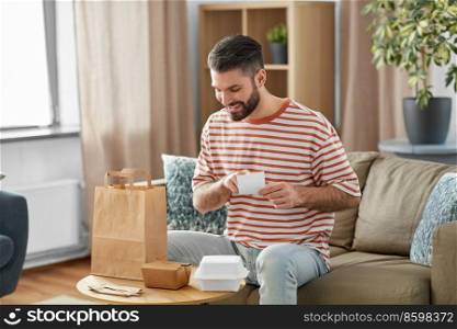 communication, leisure and people concept - happy smiling man with bill checking takeaway food order at home. man with bill checking takeaway food order at home