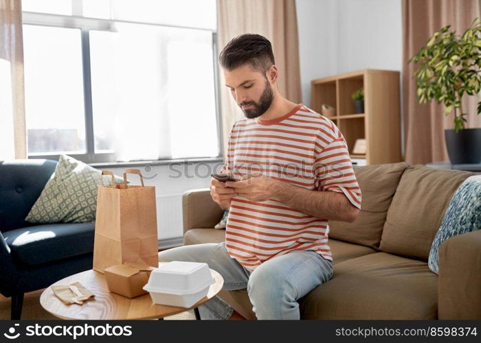 communication, leisure and people concept - man using smartphone for takeaway food order check up at home. man with phone checking food order at home