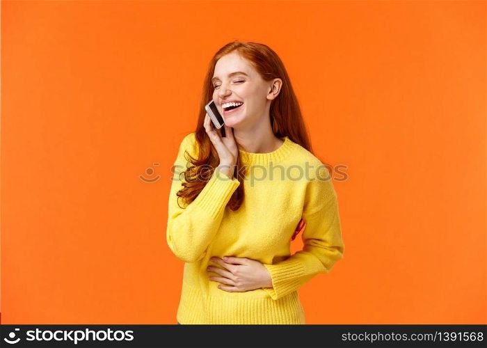 Communication, technology and people concept. Cheerful pretty redhead hipster girl talking on phone and laughing carefree, touching belly close eyes, smartphone near ear, orange background.. Communication, technology and people concept. Cheerful pretty redhead hipster girl talking on phone and laughing carefree, touching belly close eyes, smartphone near ear, orange background