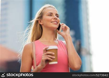 communication, technology and people concept - happy smiling young woman with coffee calling on smartphone on city street. woman with coffee calling on smartphone in city
