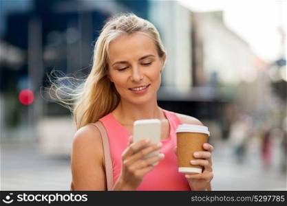 communication, technology and people concept - happy smiling young woman with coffee and smartphone on city street. woman with coffee and smartphone in city