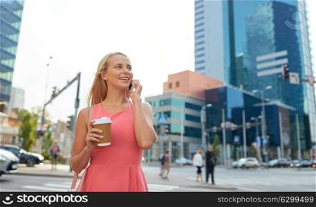communication, technology and people concept - happy smiling young woman with coffee calling on smartphone on city street. woman with coffee calling on smartphone in city