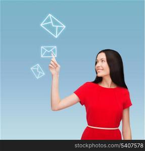 communiction and new technology concept - attractive young woman in red dress pointing her finger at envelope