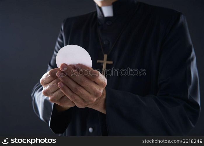 Communion wafer hostia priest in hands with cross