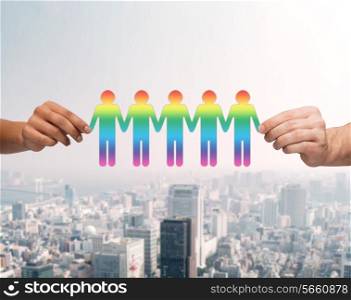 community, unity and teamwork concept - close up of multiracial couple hands holding paper chain gay people cutout over city background