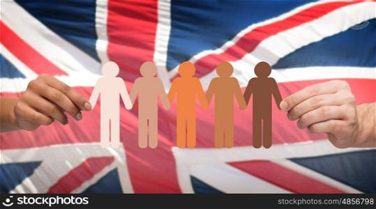 community, unity, population, race and humanity concept - multiracial couple hands holding chain of paper people pictogram over english flag background