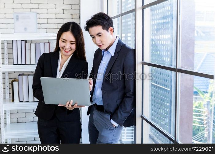 Company executive Young Asian businessman and coaching personal secretary assistant businesswoman partners while working together with laptop computer and strategy in business profit in office.