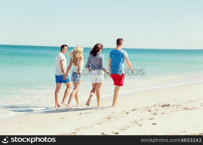 Company of young people on the beach. Company of young friends on the beach walking along the shore