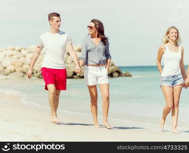 Company of young people on the beach. Company of young friends on the beach walking along the shore