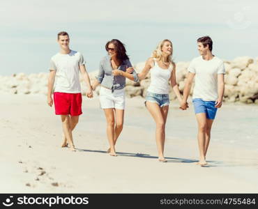 Company of young people on the beach. Company of young friends on the beach walking along the shore