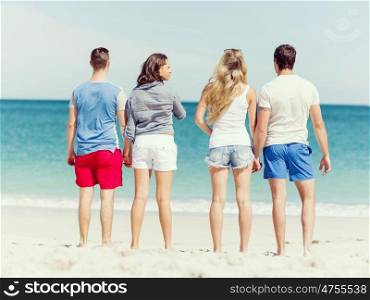 Company of young people on the beach. Company of young friends on the beach standing and looking at ocean
