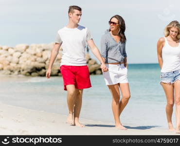 Company of young people on the beach. Company of young friends on the beach walking along the shore