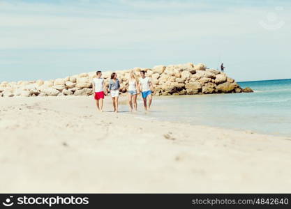 Company of young people on the beach. Company of young friends on the beach walking along the shore