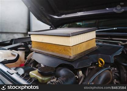 Comparing new and used car air filters placed on the engine