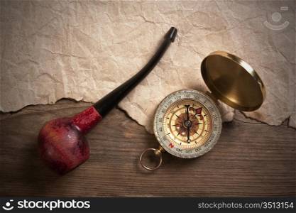 compass and a tobacco pipe on a wooden board, still-life