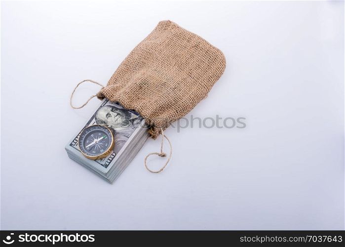 Compass and bundle of US dollarin a sack on a white background