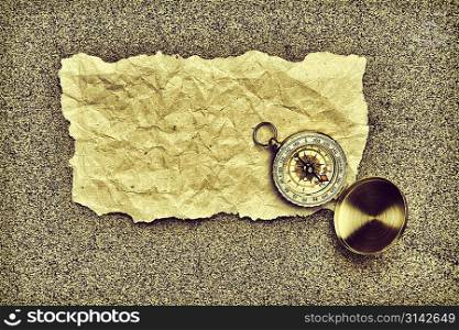 compass and old torn paper on a sandy beach