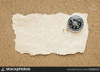 compass and old torn paper on a sandy beach