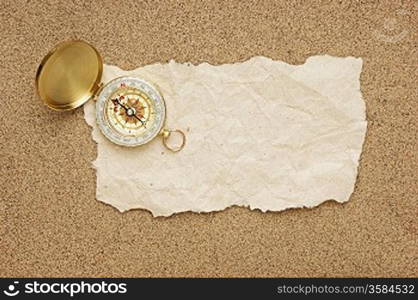 compass and old torn paper on a sandy beach