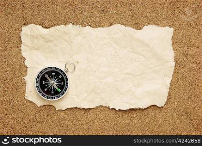 compass and old torn paper on a sandy beach