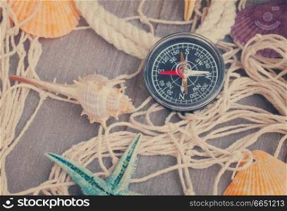 compass and shellfish on fishing net, retro toned. compass on fishing net with tag