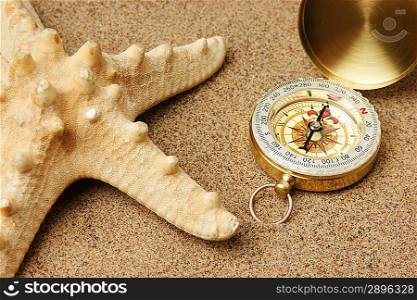 compass and starfish on a sandy beach