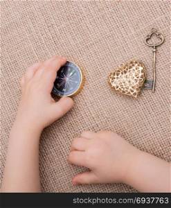 Compass, key and a heart shaped object beside a hand