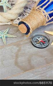 compass with  fishing net , marine rope and bottle on wooden background. compass on fishing net 