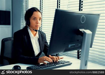 Competent female operator working on computer and talking with clients. Concept relevant to both call centers and customer service offices.. Competent female operator working on computer and while talking with clients.
