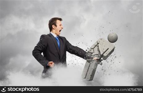 Competitive business. Angry young businessman fighting with stone opponent