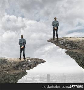 Competitive concept. Rear view of business people standing on edge of rock