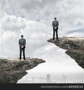 Competitive concept. Rear view of business people standing on edge of rock
