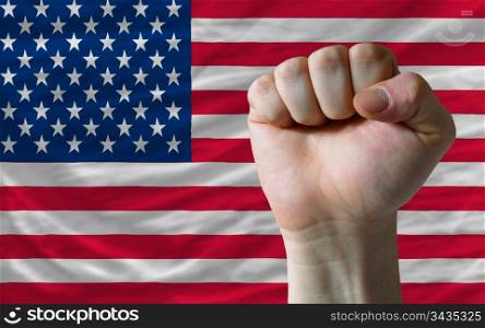complete american national flag covers whole frame, waved, crunched and very natural looking. In front plan is clenched fist symbolizing determination