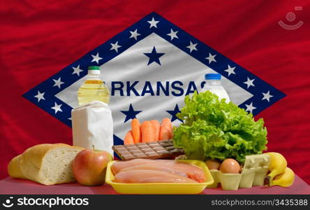 complete american state flag of arkansas covers whole frame, waved, crunched and very natural looking. In front plan are fundamental food ingredients for consumers, symbolizing consumerism an human needs