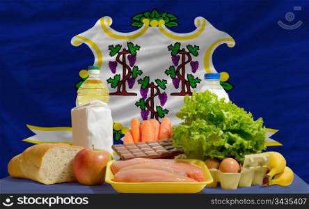 complete american state flag of connecticut covers whole frame, waved, crunched and very natural looking. In front plan are fundamental food ingredients for consumers, symbolizing consumerism an human needs