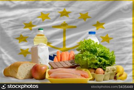 complete american state flag of rhode island covers whole frame, waved, crunched and very natural looking. In front plan are fundamental food ingredients for consumers, symbolizing consumerism an human needs