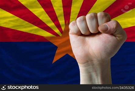 complete american state of arizona flag covers whole frame, waved, crunched and very natural looking. In front plan is clenched fist symbolizing determination