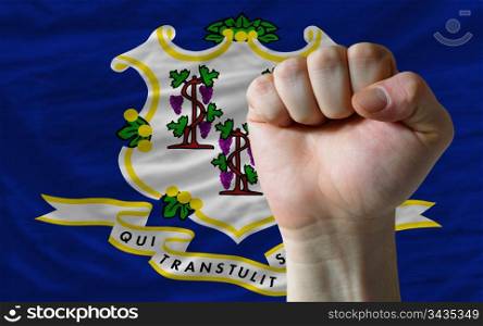 complete american state of connecticut flag covers whole frame, waved, crunched and very natural looking. In front plan is clenched fist symbolizing determination