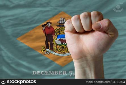 complete american state of delaware flag covers whole frame, waved, crunched and very natural looking. In front plan is clenched fist symbolizing determination