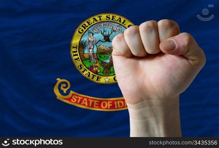complete american state of idaho flag covers whole frame, waved, crunched and very natural looking. In front plan is clenched fist symbolizing determination