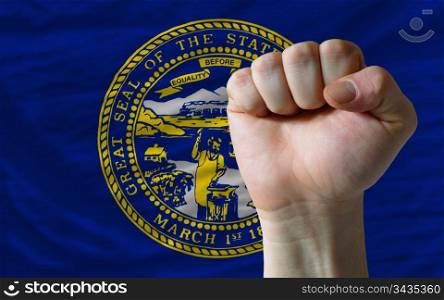 complete american state of nebraska flag covers whole frame, waved, crunched and very natural looking. In front plan is clenched fist symbolizing determination