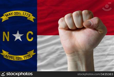 complete american state of north carolina covers whole frame, waved, crunched and very natural looking. In front plan is clenched fist symbolizing determination