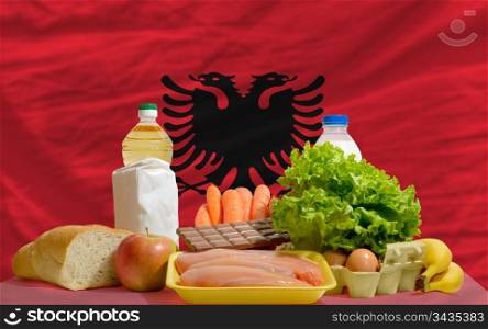 complete national flag of albania covers whole frame, waved, crunched and very natural looking. In front plan are fundamental food ingredients for consumers, symbolizing consumerism an human needs