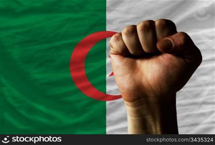 complete national flag of algeria covers whole frame, waved, crunched and very natural looking. In front plan is clenched fist symbolizing determination
