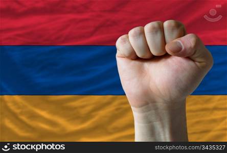 complete national flag of armenia covers whole frame, waved, crunched and very natural looking. In front plan is clenched fist symbolizing determination